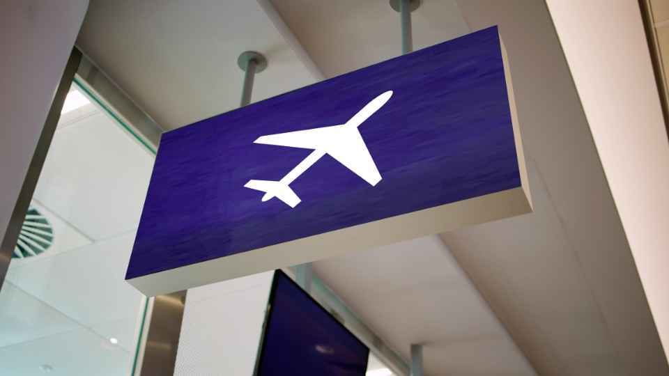 Airport sign with a white airplane icon indicating the direction of flight departures.